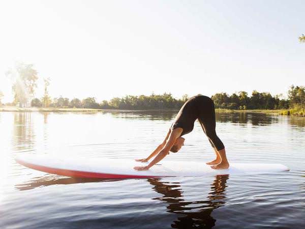 donna che fa yoga sulla tavola da surf
